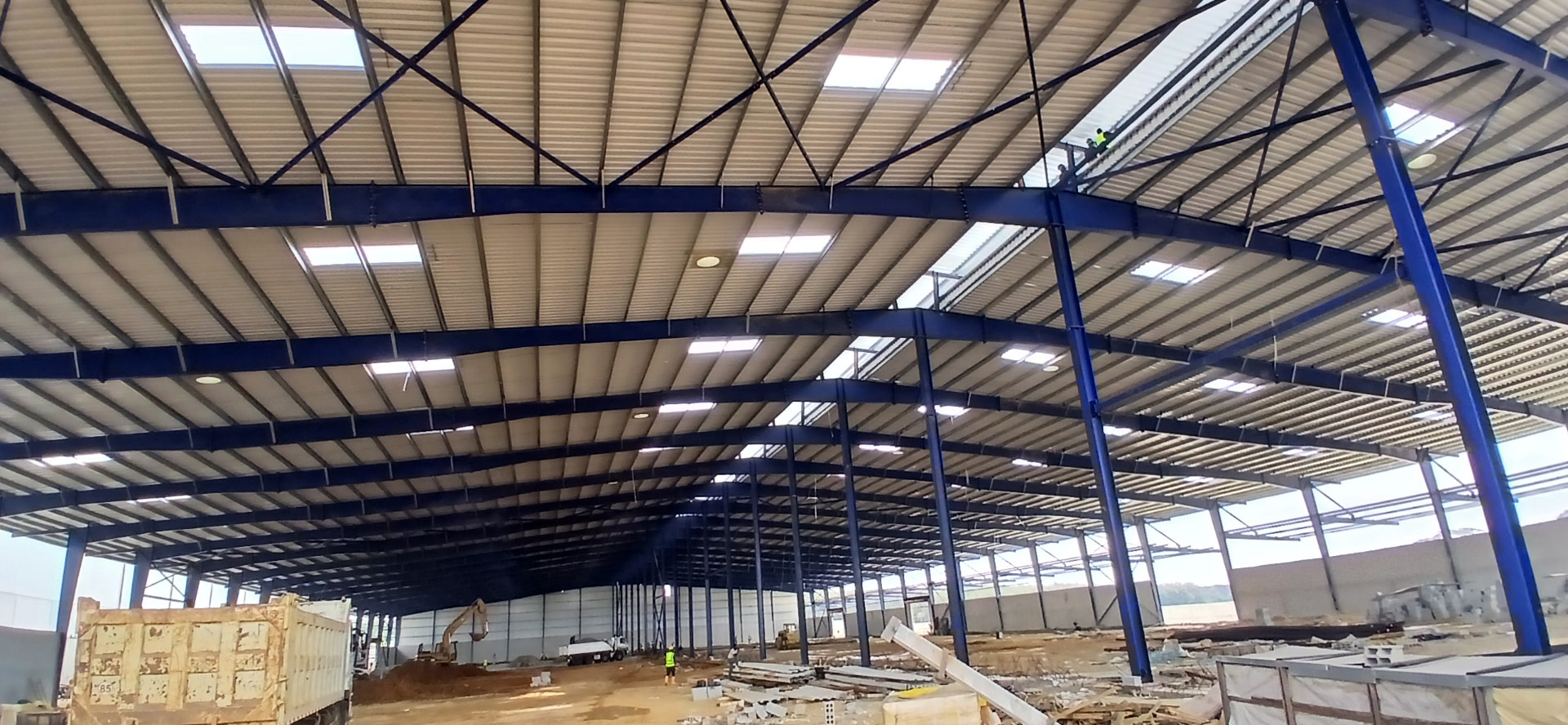 Charpente industrielle 20 000 m² à Yopougon PK24 : structure métallique bleue, pannes, portiques et couverture en cours de finition — vue 2