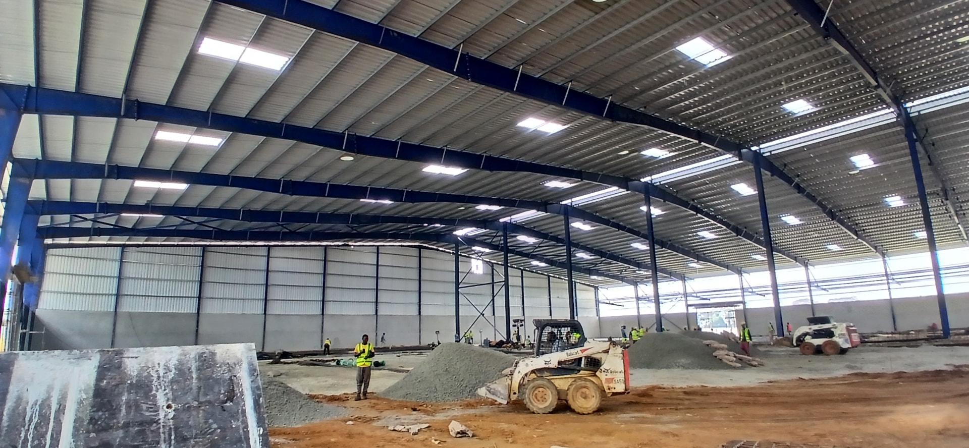 Charpente industrielle 20 000 m² à Yopougon PK24 : structure métallique bleue, pannes, portiques et couverture en cours de finition — vue 4