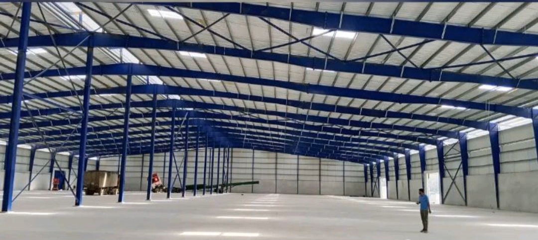 Charpente industrielle 20 000 m² à Yopougon PK24 : structure métallique bleue, pannes, portiques et couverture en cours de finition — vue 1